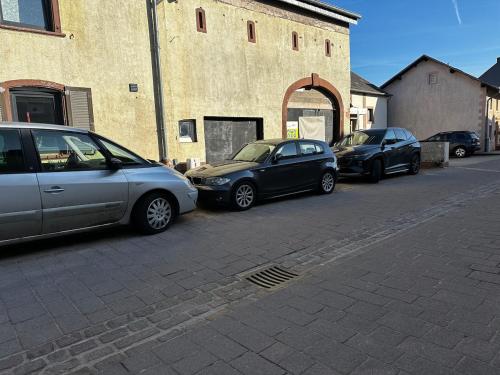 three cars parked in a parking lot next to a building at Apartment with us! in Mertzig