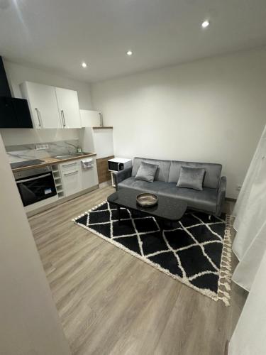 a living room with a couch and a kitchen at Normandy suites in Igé
