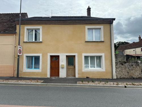 a yellow house with a brown door on a street at Normandy suites in Igé