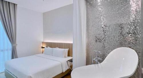 a white bedroom with a bed and a chair at S Hotel in Johor Bahru