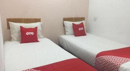 two beds in a room with red and white pillows at OYO 89671 Changlun Star Motel in Changlun