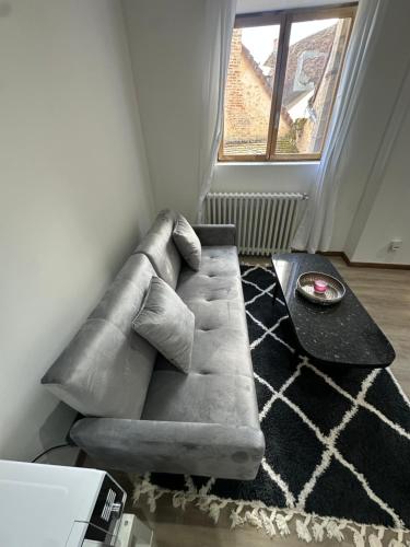 a gray couch in a living room with a window at Normandy suites in Igé
