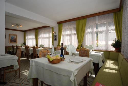 ein Esszimmer mit Tischen, Stühlen und Fenstern in der Unterkunft Hotel Ancora in Moena