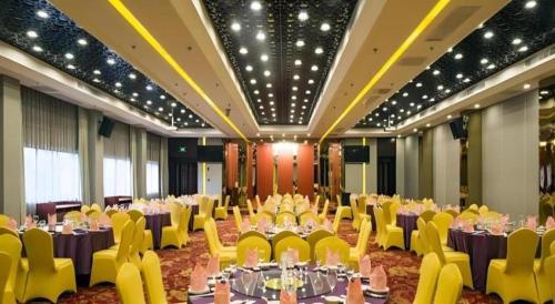 a banquet hall with purple tables and yellow chairs at Quanzhou Overseas Chinese Hotel in Quanzhou