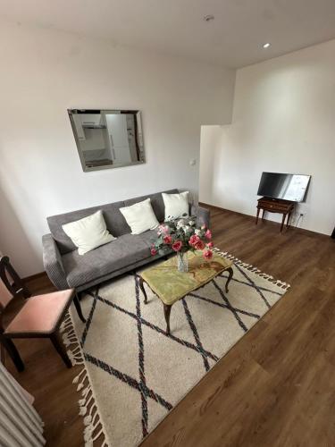 a living room with a couch and a table and a television at Normandy suites in Igé