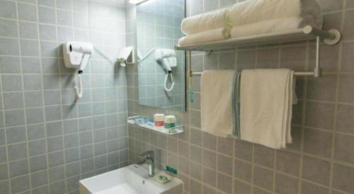 a bathroom with a sink and a mirror and towels at Jinjiang Inn Style Tianjin Wuqing Traditional Chinese Medical Hospital in Tianjin