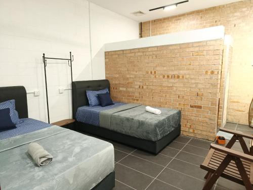ein Schlafzimmer mit zwei Betten und einer Ziegelwand in der Unterkunft Single-Storey Bungalow 1 to 14pax Industrial Style in Pelabuhan Kelang