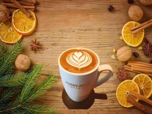 a cup of coffee sitting on top of a wooden table at James Joyce Coffetel·Shijiazhuang Economic and Technological Development Zone Chuangye Road in Shijiazhuang