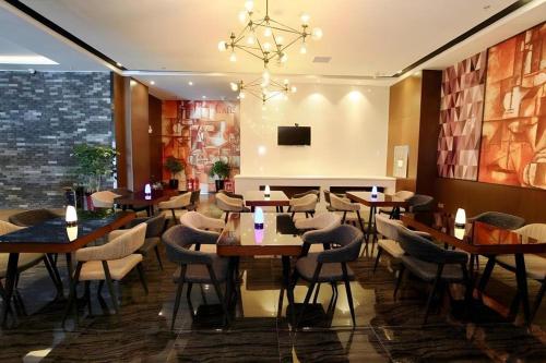 a restaurant with wooden tables and chairs and a chandelier at Zmax Changzhi Bayi Square in Changzhi