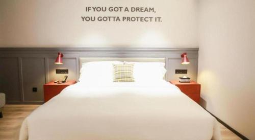 a bedroom with a bed with a quote on the wall at City Comfort Premier Hotel Xiaogan Anlu Railway Station Dongda Times Square in Xiaogan