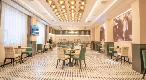 a dining room with tables and chairs and a television at City Comfort Premier Hotel Xiaogan Anlu Railway Station Dongda Times Square in Xiaogan