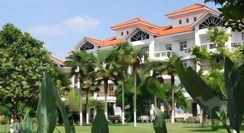 a large white building with trees in front of it at Kunming Dianchi Garden Hotel & Spa in Kunming