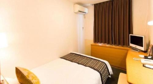 a hotel room with a bed and a desk with a computer at Hotel Areaone Miyazaki in Miyazaki