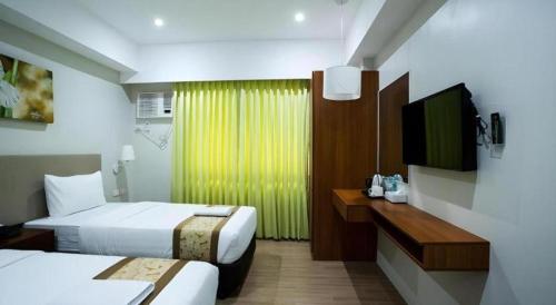 a hotel room with two beds and a flat screen tv at Hotel Fleur de Liz in Panglao