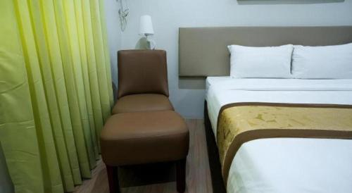 a bedroom with a bed and a chair in it at Hotel Fleur de Liz in Panglao