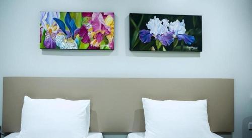 two paintings of flowers on the wall above a bed at Hotel Fleur de Liz in Panglao