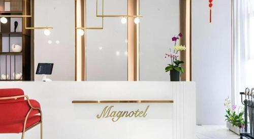 a lobby with a red chair and a counter at Magnotel Hotel Dongxing Guomen Port in Fangcheng