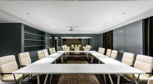 a conference room with a large white table and chairs at Magnotel Hotel Dongxing Guomen Port in Fangcheng