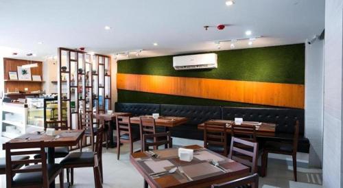 a restaurant with wooden tables and a green wall at Hotel Fleur de Liz in Panglao