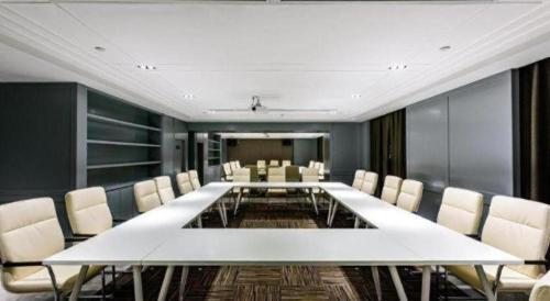 a conference room with a large white table and chairs at Magnotel Hotel Dongxing Guomen Port in Fangcheng