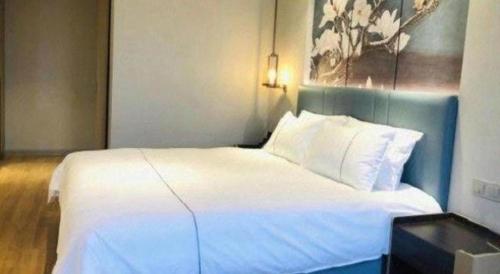 a large white bed in a hotel room at Magnotel Hotel Dongxing Guomen Port in Fangcheng