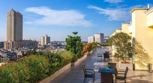 a balcony with tables and chairs and a view of a city at Magnotel Hotel Dongxing Guomen Port in Fangcheng