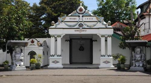 a white building with statues in front of it at Super OYO 1788 House 24 in Yogyakarta