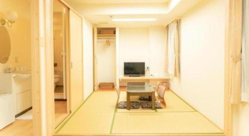 a living room with a tv and a table in a room at Smile Hotel Nishiakashi in Kobe
