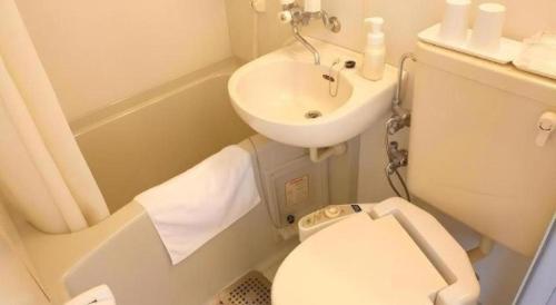 a small bathroom with a toilet and a sink at Smile Hotel Nishiakashi in Kobe