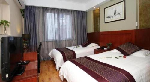 a hotel room with two beds and a television at Hangzhou Bokai Westlake Hotel in Hangzhou