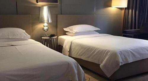 a bedroom with two beds with white sheets and pillows at Ramada by Wyndham Xi'an Bell Tower in Xi'an