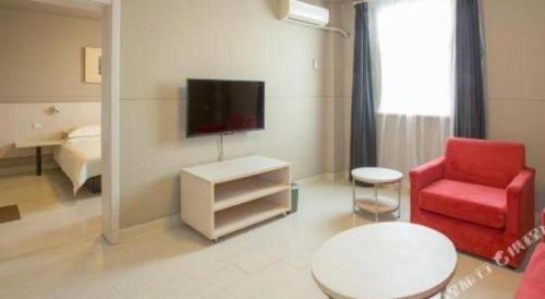 a living room with a red chair and a tv at Jinjiang Inn Luoyang Wangcheng Park Metro Station in Luoyang