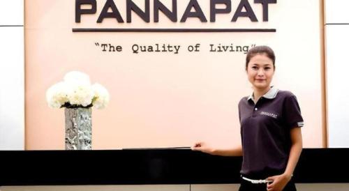 a woman standing in front of a table with a sign at Pannapat Place in Bangkok