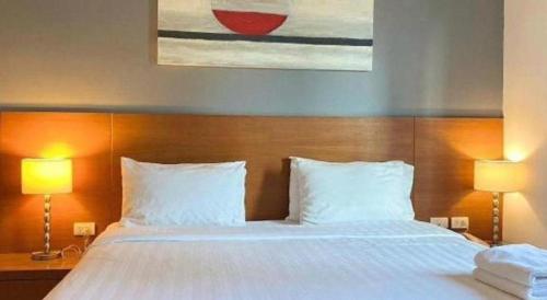 a bedroom with a large white bed with two lamps at Pannapat Place in Bangkok