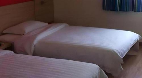 two beds in a hotel room with white sheets at 7 Days Inn Siping Xinhua Street in Siping