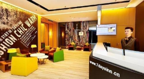 a man standing at a podium in a room with furniture at 7 Days Premium Xi'an Dayan Tower Xiaozhai Metro Station in Xi'an