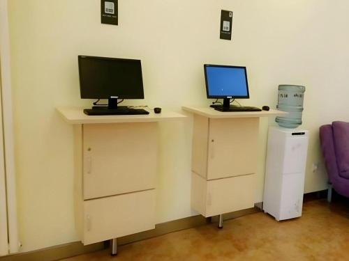 a desk with two computer monitors on top of it at 7 Days Inn Nanjing Xinjiekou Changfu Street Metro Station in Nanjing