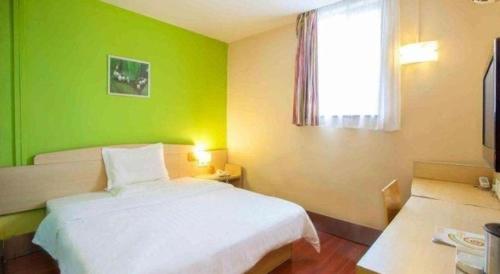 a green bedroom with a white bed and a window at 7 Days Inn Nanjing Xinjiekou Changfu Street Metro Station in Nanjing