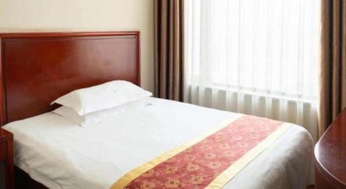 a white bed with a wooden head board and a window at GreenTree Inn Datong YundinGYAyuan Express Hotel in Datong