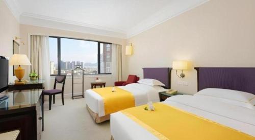 a hotel room with two beds and a table and chairs at Shantou Golden Gulf Hotel in Shantou