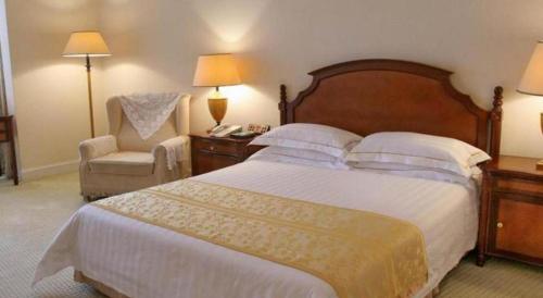 a hotel room with a large bed and a chair at Shantou Golden Gulf Hotel in Shantou