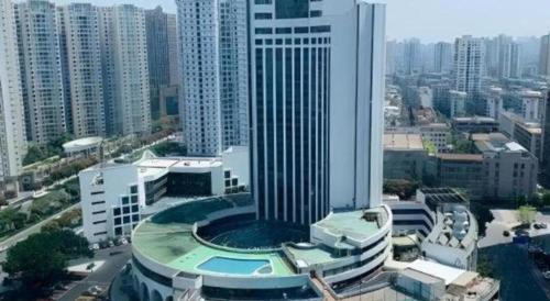 a large building with a pool in the middle of a city at Shantou Golden Gulf Hotel in Shantou