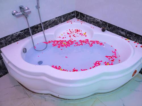 eine Badewanne mit roten Streuseln in einem Badezimmer in der Unterkunft La French villa in Puducherry