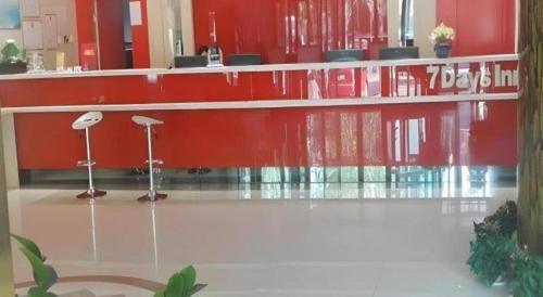 a lobby with red walls and two stools at 7 Days Inn Dongsheng Railway Station in Ordos