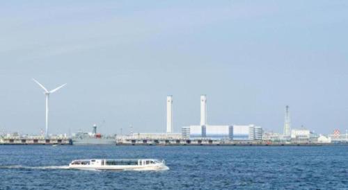 a boat in the water with a city in the background at Hotel Edit Yokohama in Yokohama
