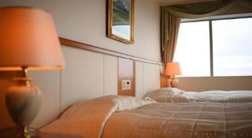 a bedroom with two beds next to a window at Grand Hotel New Oji in Tomakomai