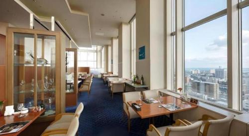 a restaurant with tables and chairs and a large window at Grand Hotel New Oji in Tomakomai