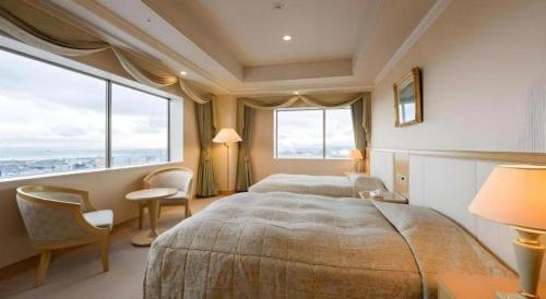 a bedroom with two beds and a large window at Grand Hotel New Oji in Tomakomai
