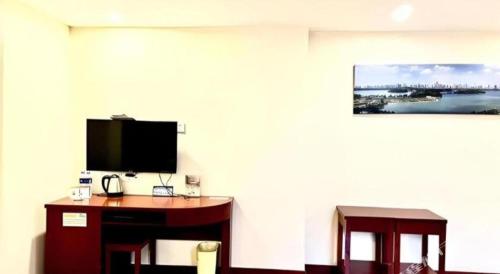 a room with a desk and a tv on a wall at GreenTree Inn Nanjing Confucius Temple Sanshan Street Subway Station Express Hotel in Nanjing