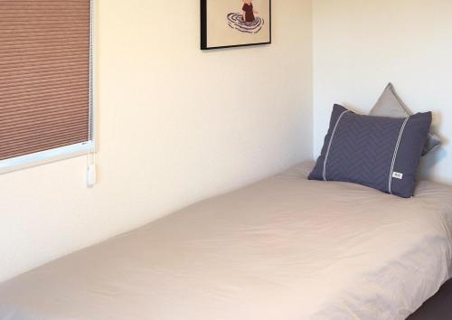a bedroom with a bed with a pillow and a window at The SAKAI newly built home 7 mins walk from Train Station in Abiko
